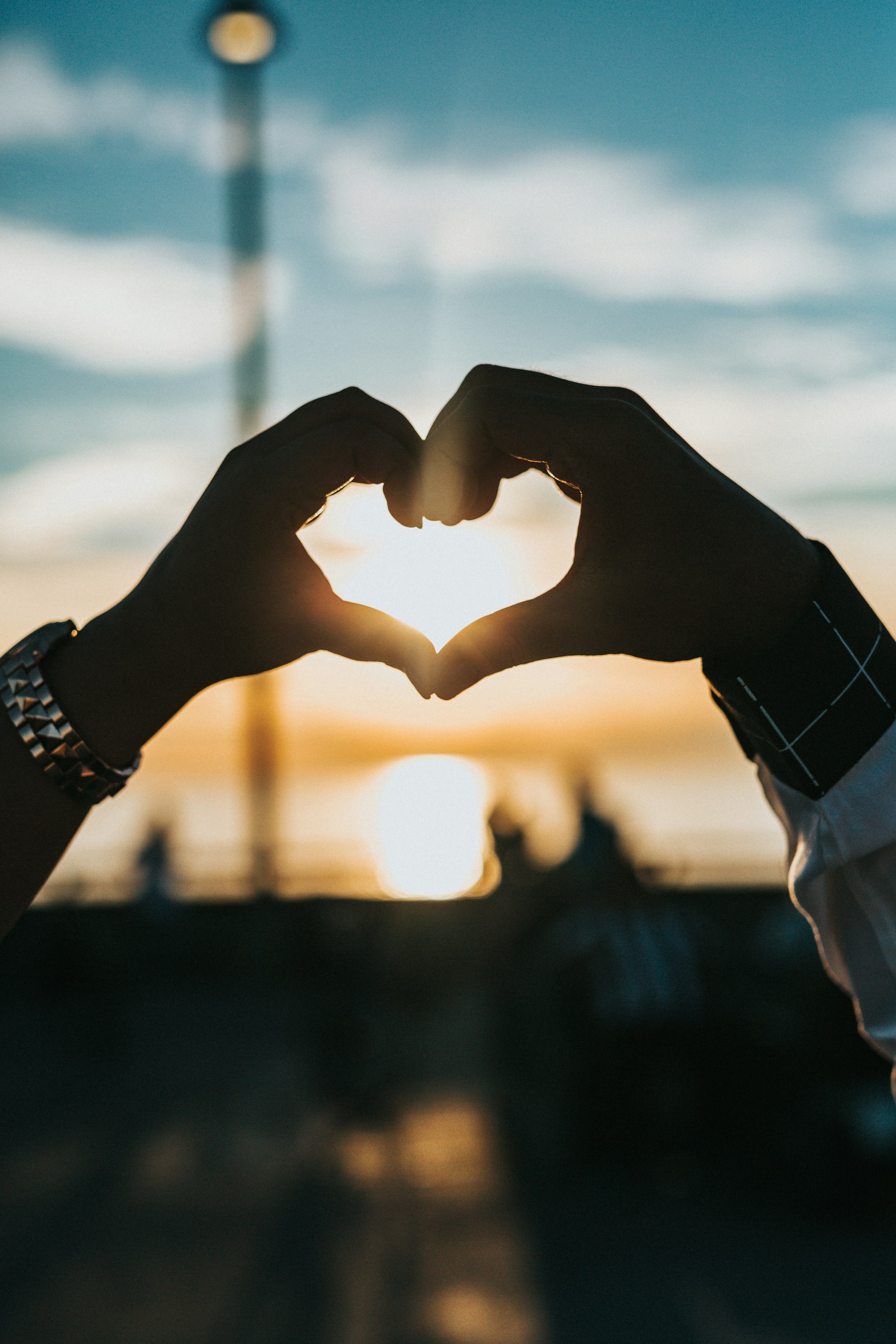 Couple making a heart with their hands at sunset